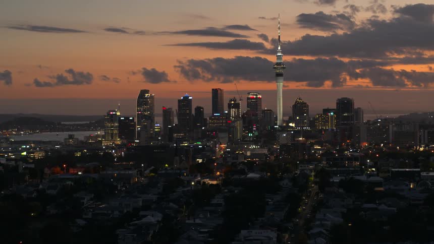 Aerial view of illuminated city buildings with skyscraper being silhouetted against the red sky at sunset