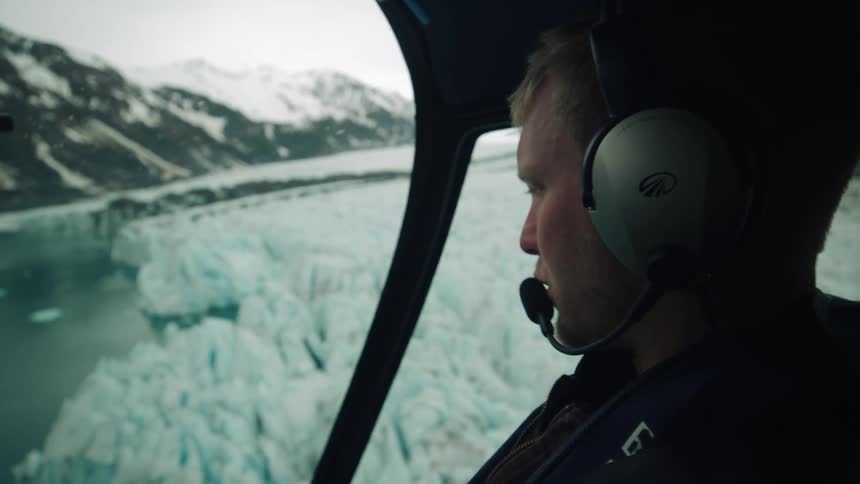 A man is flying a helicopter over the ice