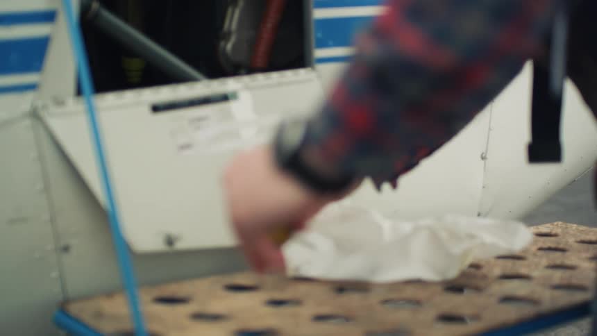 A man standing next to an airplane pulls a tool out of material