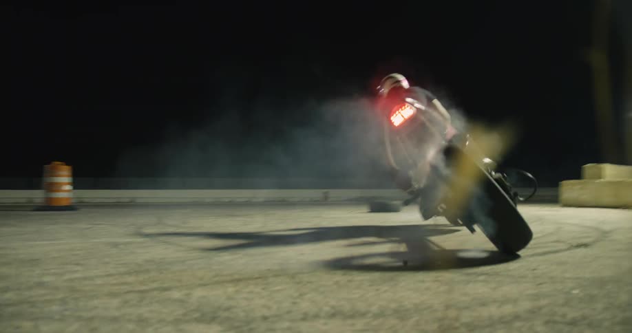 Motorcyclist turns motorcycle on track at night burning rubber