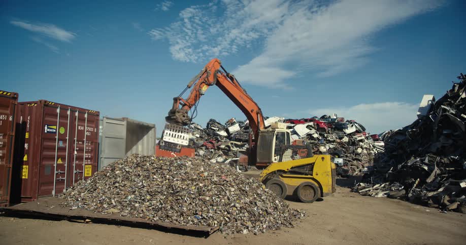 A bull dozer lifts up debris from a pile of rubble at a scrap yard