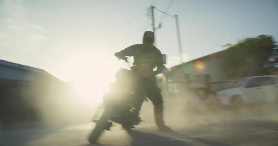 A man rides his motorcycle in circles in a dirt parking lot