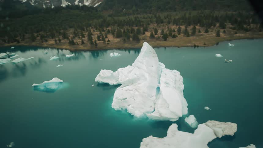 Icebergs line the shore in the blue water