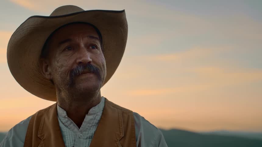 Emotional man with cowboy hat mustache white shirt and brown vest looking around and thinking