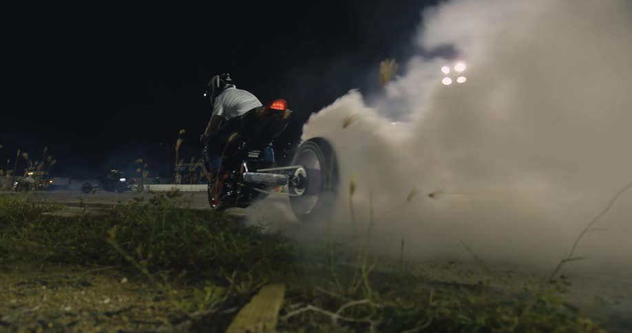 Man burning rubber on a motorcycle on a race track at night