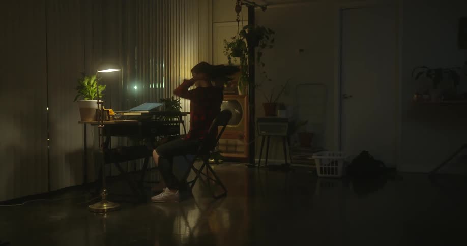 Woman puts on sweater from laundry basket and sits at desk