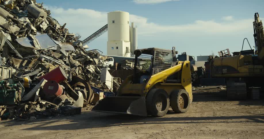 A man climbs into a bulldozer at a junk yard and drives off