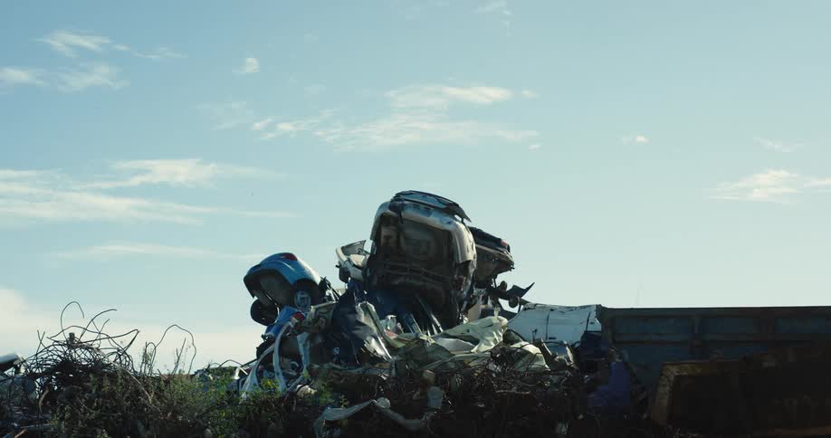 A pile of wrecked vehicles are stacked in the junkyard
