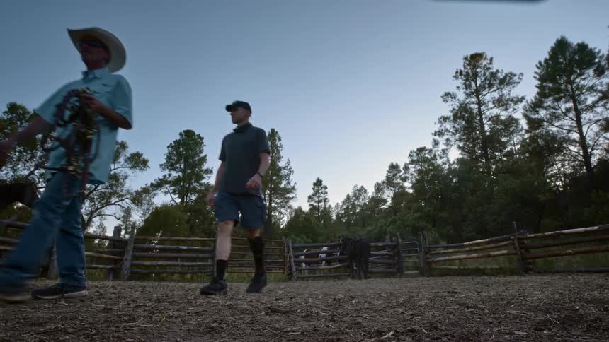 Two men walking through a fenced in area of dirt