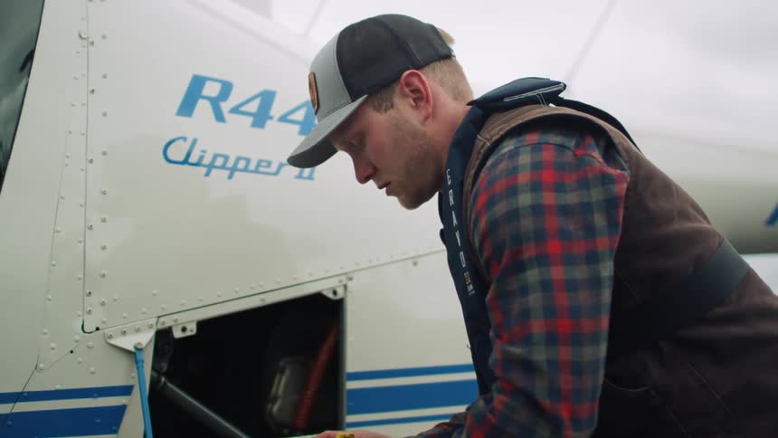 Young mechanic changes fluids on a helicopter engine on an airfield