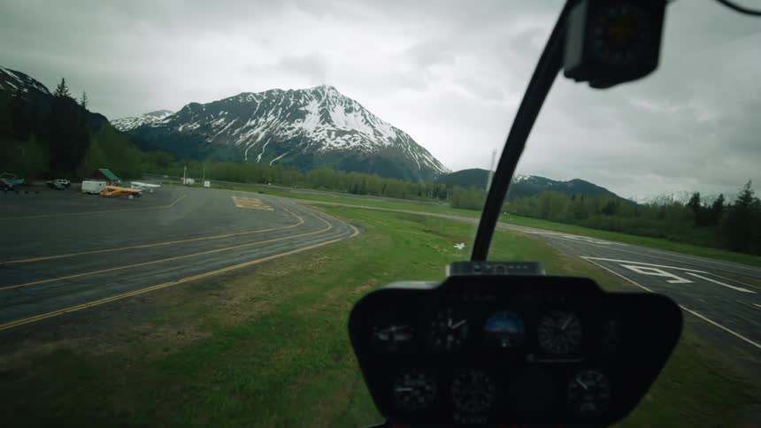 A plane lands on the tarmac at a small airport near mountains