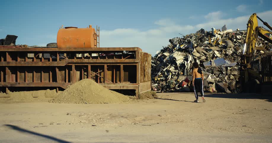 Black person walking through scrap yard
