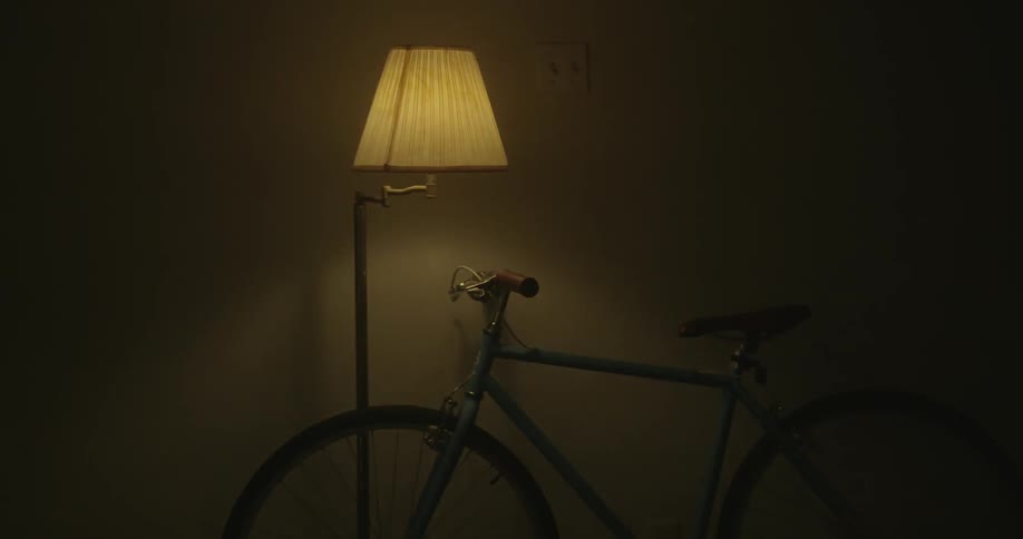 A bike is hanging on the wall as a lamp blinks rapidly