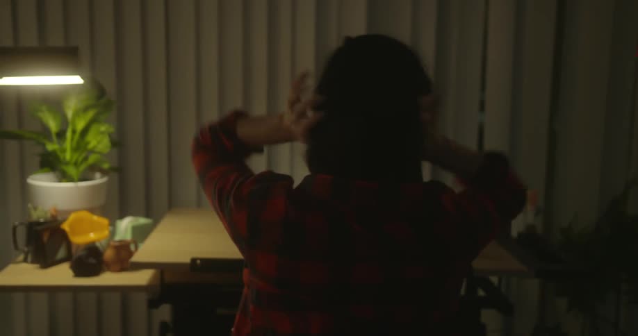 A woman walks through a home then puts on her coat and sits