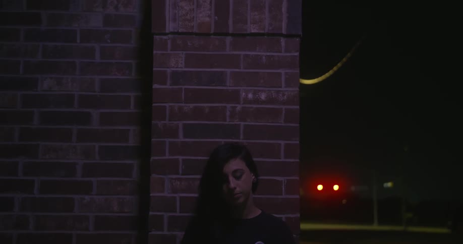 A dark haired woman standing in front of a brick building