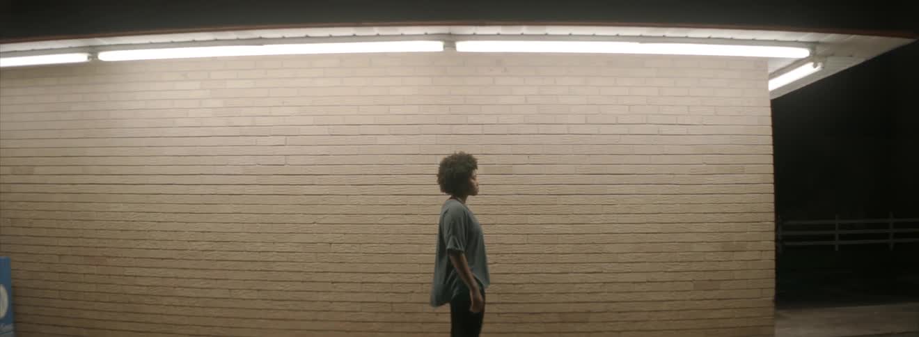 A person is standing near a brick wall under a light