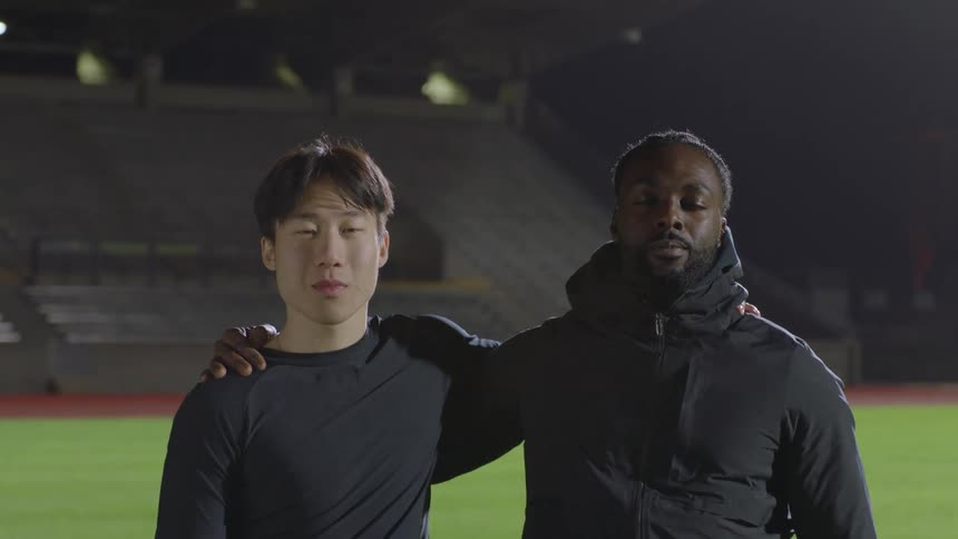 Two teammates in an empty stadium putting their arms over each others shoulders