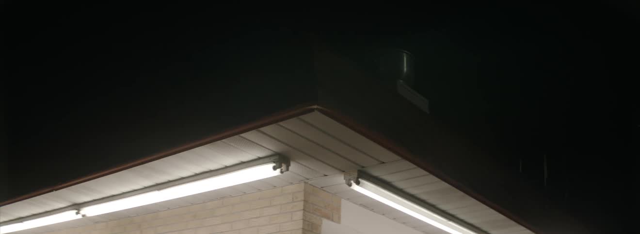 Fluorescent lights hanging from the overhang of a building