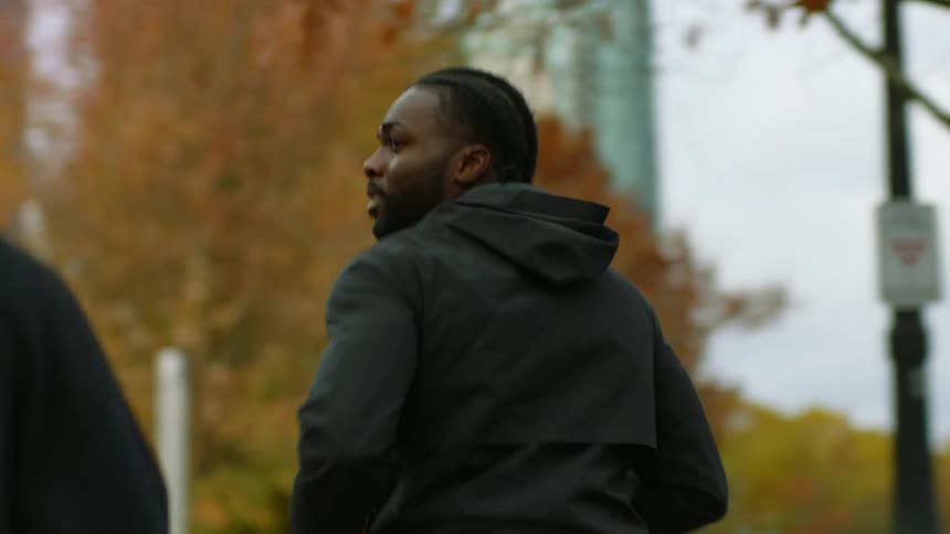 Two friends jogging on a park next to the city at fall