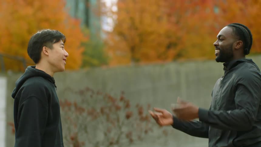Two friends shake hands and hug greeting each other in the city at fall