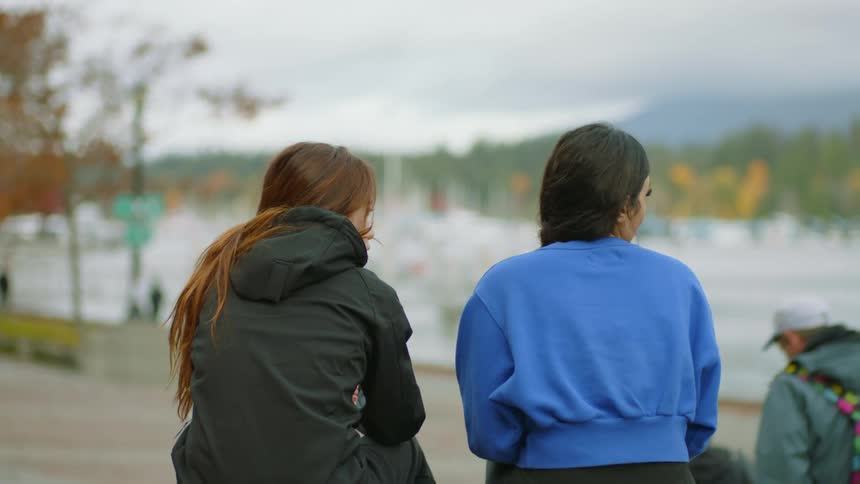Two friends sit and talk in the park on a fall day