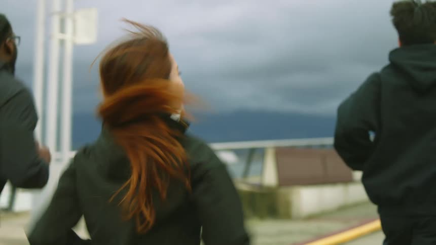 Group of friends jogging together on a street on an overcast day