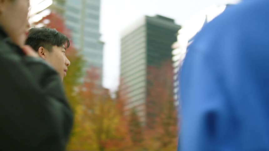 Four friends jog along road then stop with skyscrapers in background