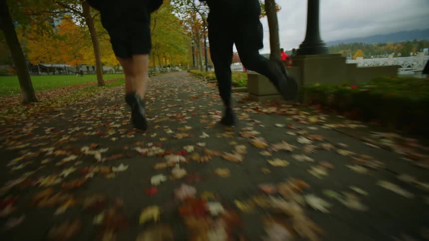 Friends wearing black sports clothes jogging on a park next to the city