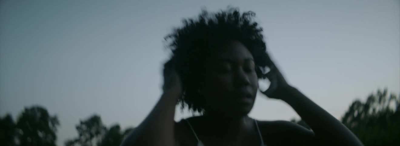 A woman walks on a field and grabs her head