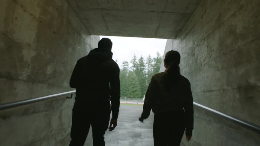 A man and woman walking out of a tunnel outdoors