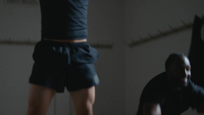 Two friends working out together inside a dimly lit room