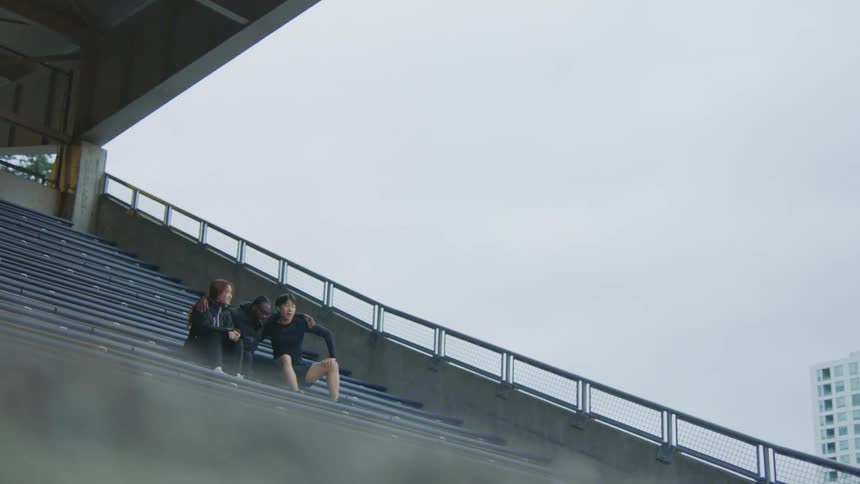 Group of friends talking while sitting on the stadium bleachers near the city
