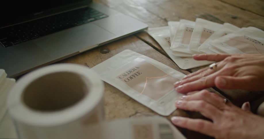 A woman attaches coffee labels to a white sheet