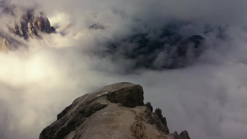 Aerial view of clouds surrounding a mountain peak at morning