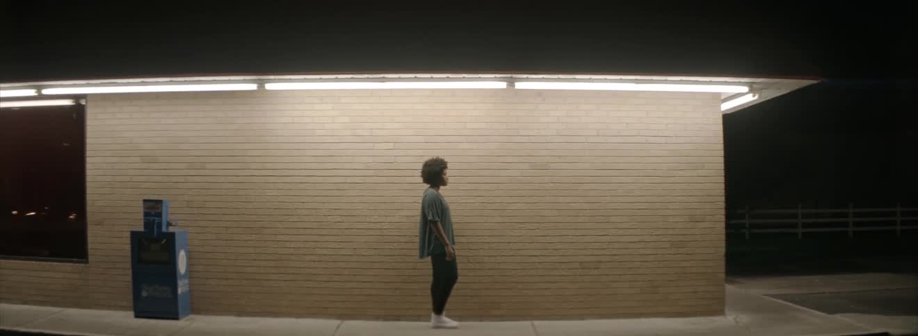 A woman stands outside of a brick building at night