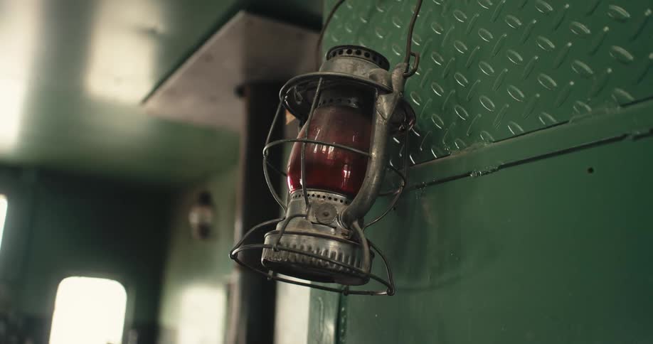 Lantern hangs against green painted wall as windows let in light