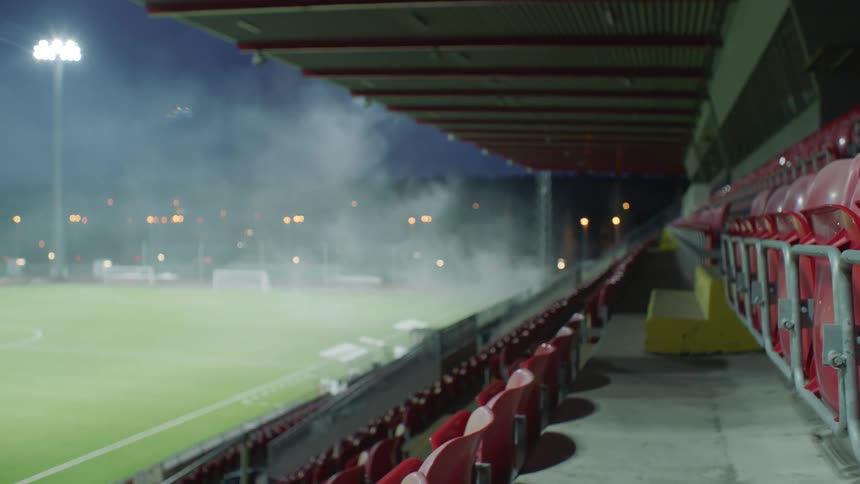 Row of red seats on the stadium next to clouds of steam or fog at night
