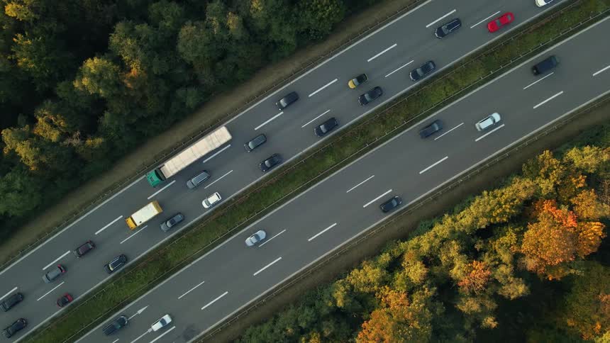 Aerial view of traffic on a busy highway and trees along the side of the road in fall colors