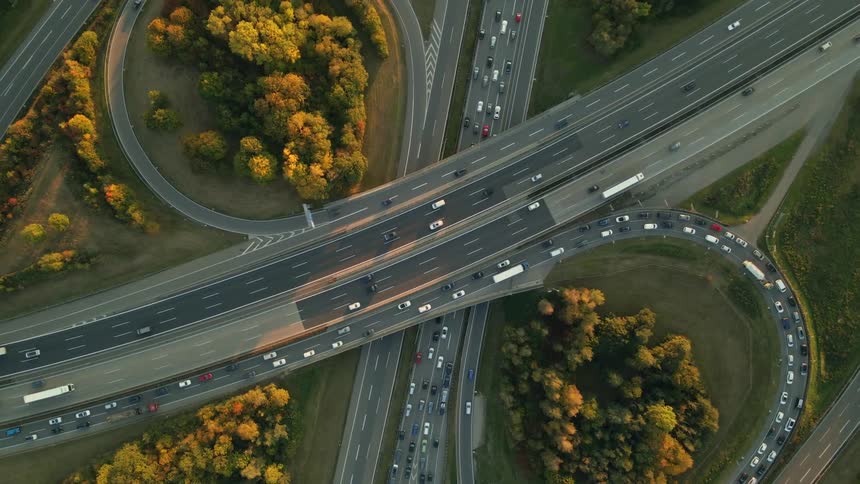 Aerial view of a busy highway intersection and trees along the side of the road in fall colors