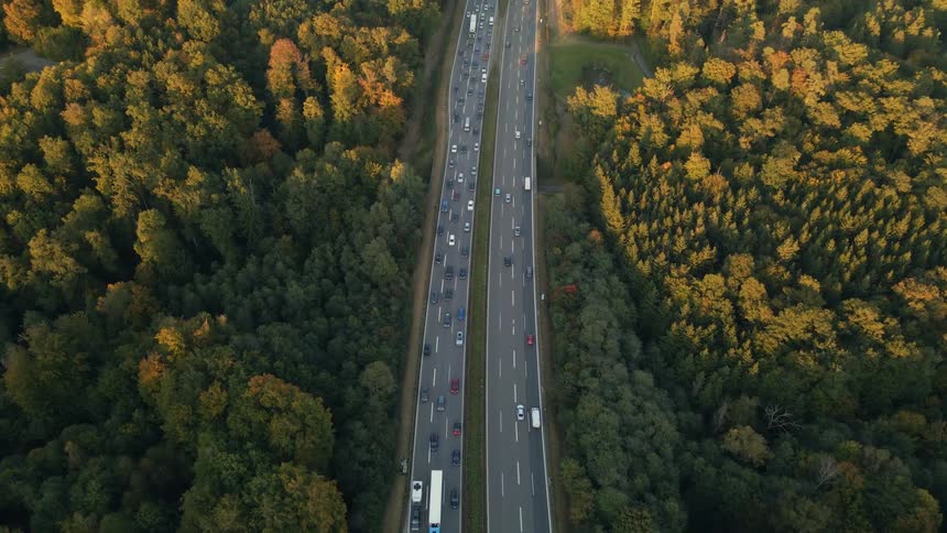 Aerial view of a busy highway and trees along the side of the road in fall colors