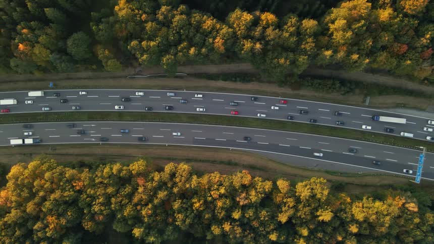 Aerial view of a busy highway and trees along the side of the road in fall colors