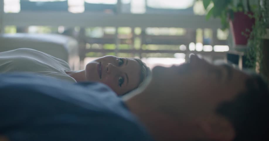 Young happy couple laying in bed looking at each other at home