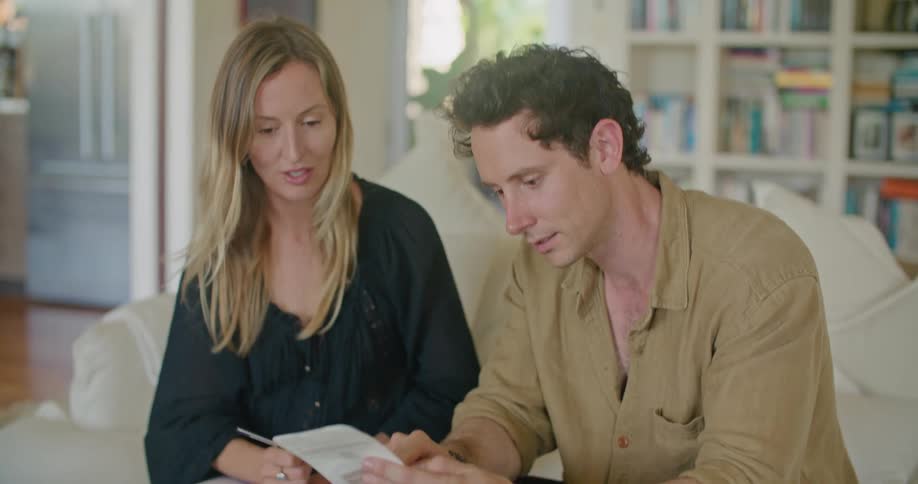 A man and woman look at brochures while sitting on the couch