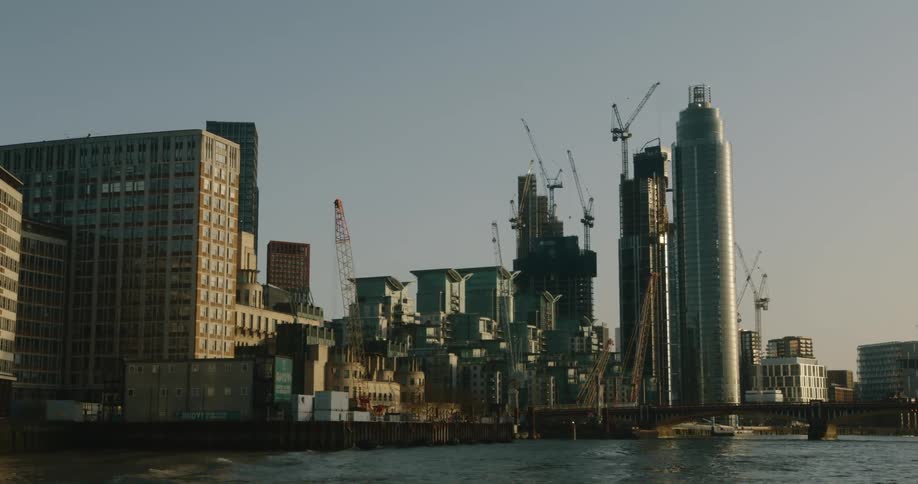 Construction cranes towering over the skyscrapers on the waterfront city skyline at morning