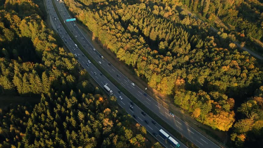 Aerial view of a busy highway and trees along the side of the road in fall colors