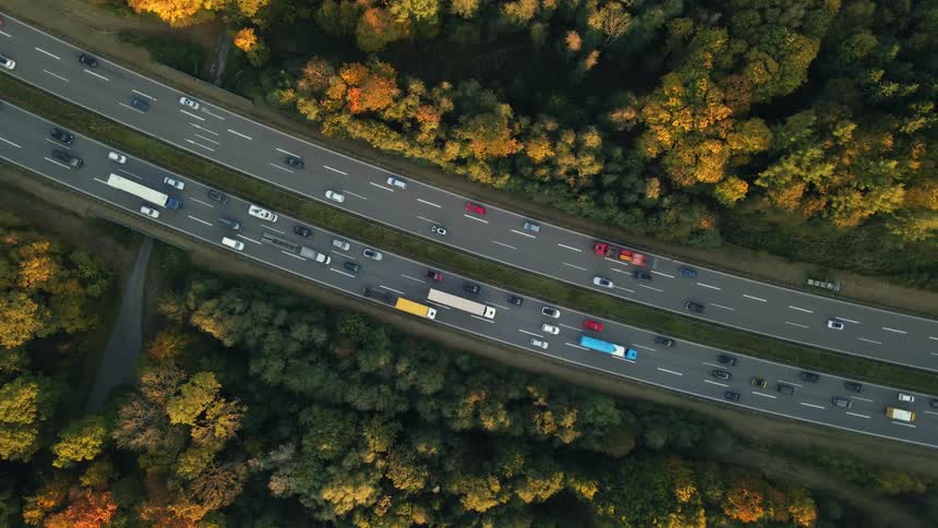 Aerial view of traffic on a busy highway and trees along the side of the road in fall colors