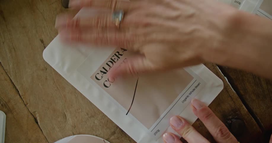 A woman attaches a sticky label to an empty package on a wooden table