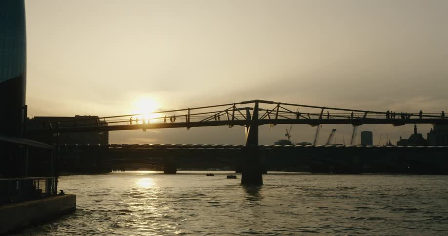 London Millennium Bridge at sunset with pedestrians walking