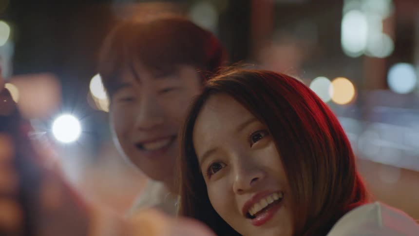 Young asian couple take selfies with a camera in the city at night