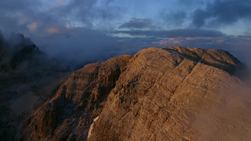 Clouds floating around a rocky mountain range at dawn in nature
